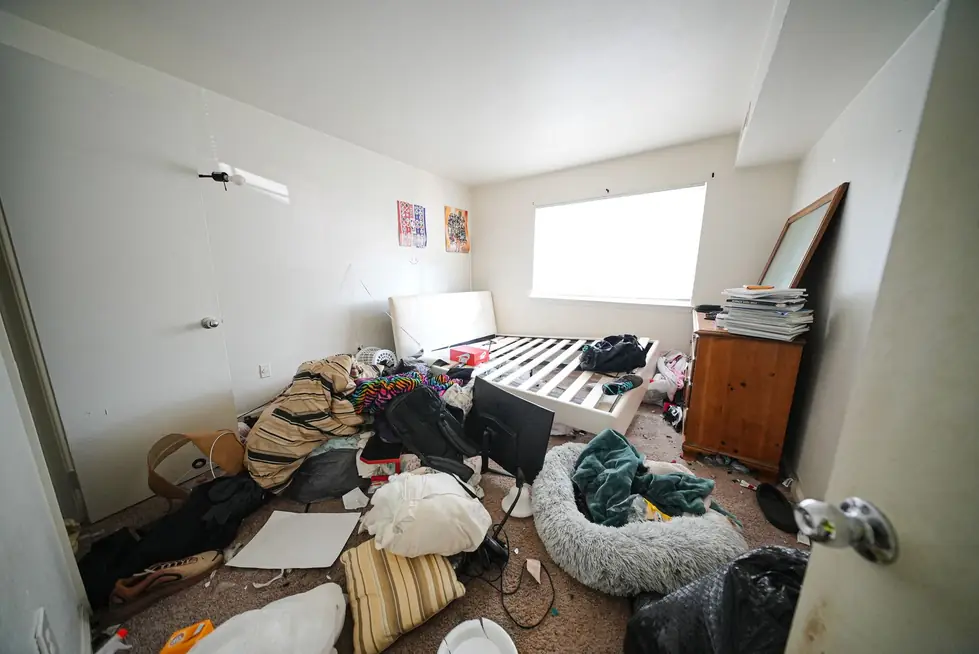 Bedroom floor covered in clothes, bedding and boxes before a cleanout