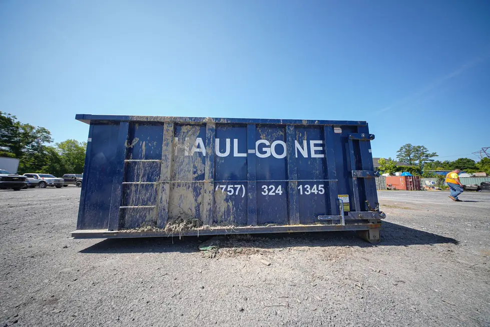 Empty navy Haul Gone roll-off dumpster standing alone on an open lot