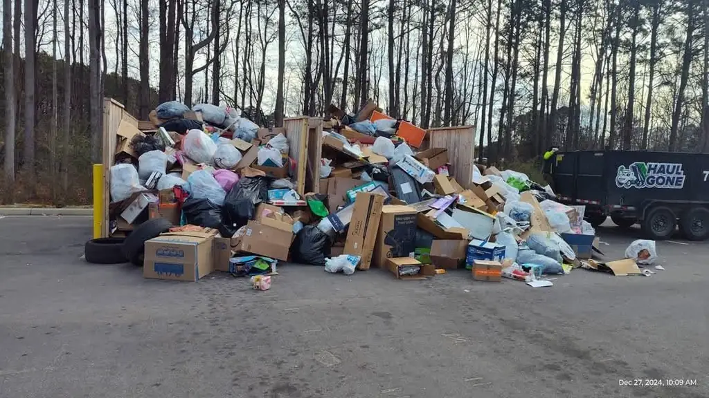 Large pile of bagged junk and boxes beside a Haul Gone trailer at a cleanout